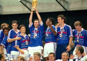 Zidane levanta o troféu do França 98, com Deschamps no canto direito da imagem.